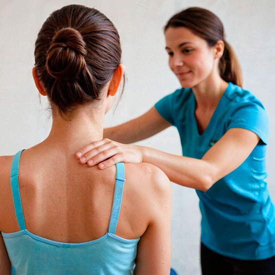 Fisioterapeuta u osteópata valorando la espalda y el hombro de una paciente en consulta